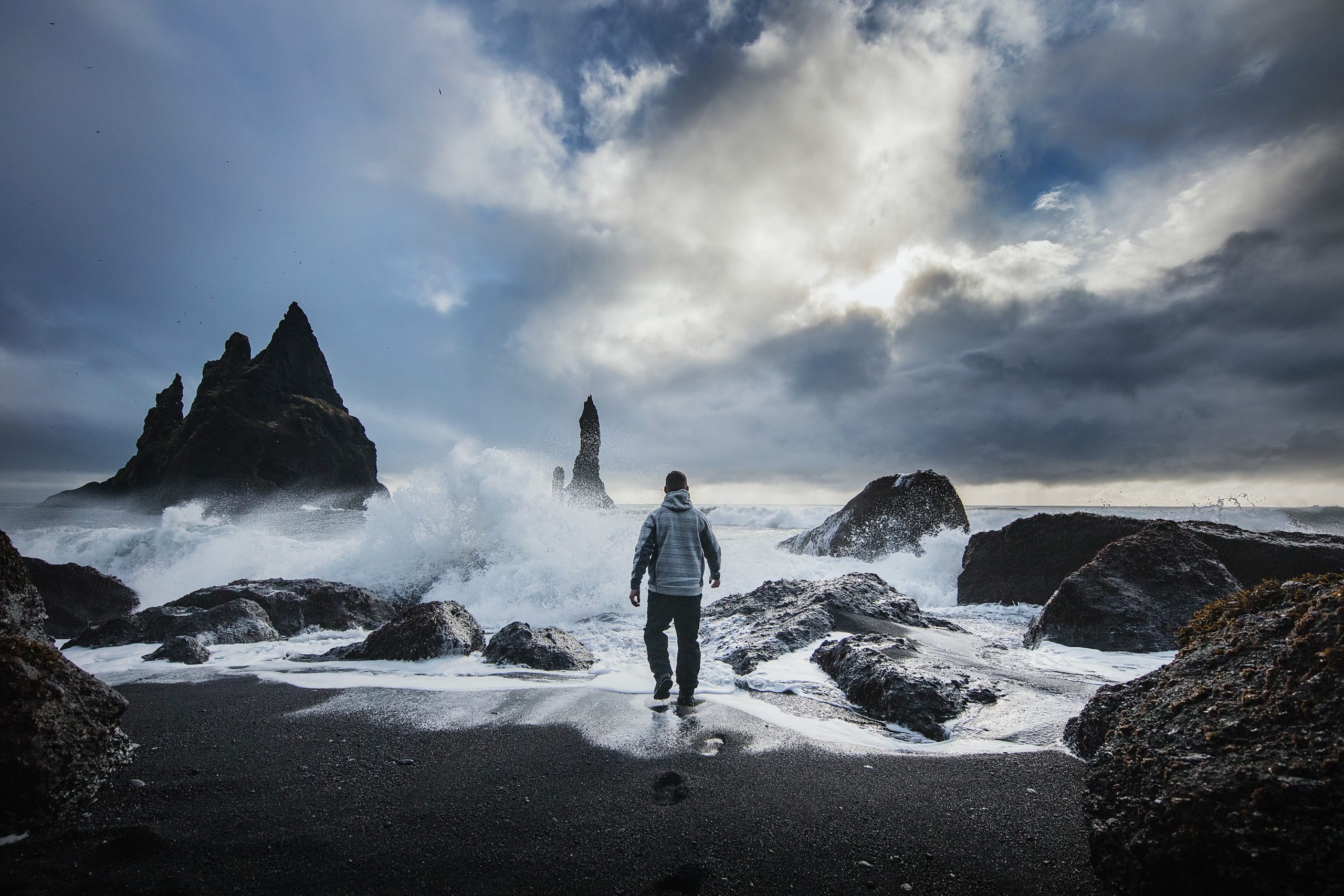 A man standing too close to the shoreline at Reynisfjara beach in Iceland