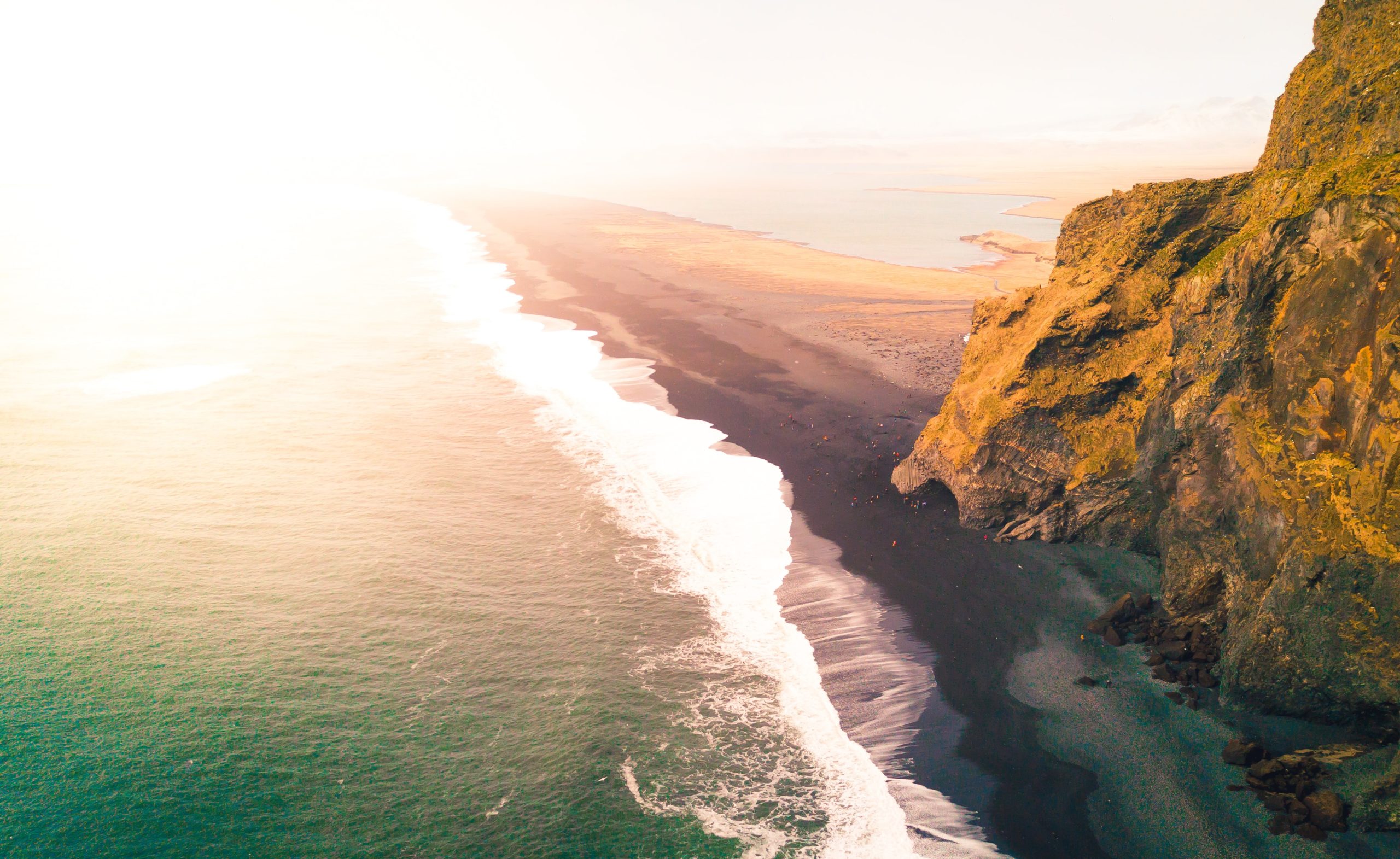 Sunlight pours over the black sands of Reynisfjara beach in Iceland