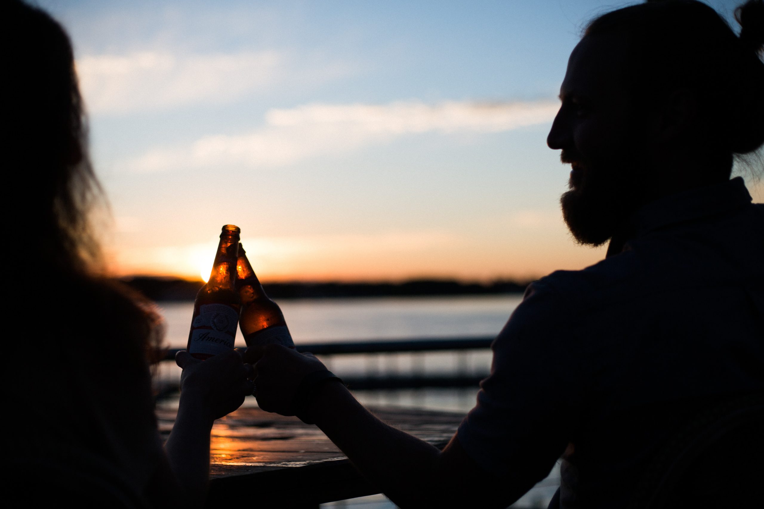 Two people drinking bottled beer outside